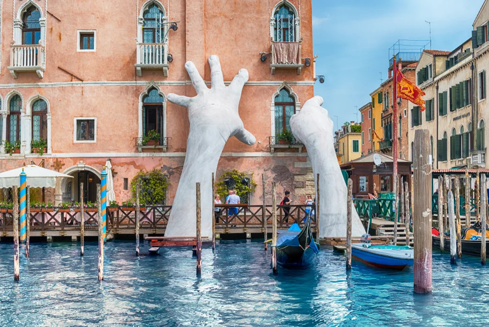 Patung karya Lorenzo Quinn di Venesia yang menggambarkan ancaman naiknya permukaan laut akibat perubahan iklim. Gambar: Shutterstock